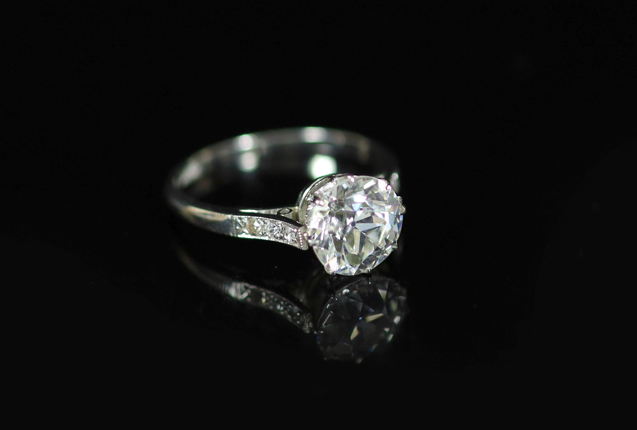 A platinum and single stone diamond ring, with diamond set shoulders